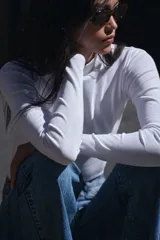 Camiseta blanca de manga larga con cuello alto y corte ajustado.