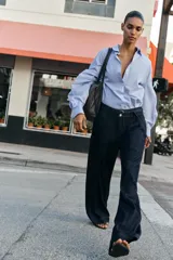 Jeans de tiro alto con corte bootcut, confeccionados en denim azul oscuro. Presentan costuras verticales decorativas en el frente, bolsillos laterales y cinturón del mismo tejido con hebilla metálica.