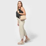 Cartera bandolera color beige con diseño acolchado y correa larga negra regulable.