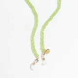 Correa para lentes verde con cuentas acrílicas y terminales de goma transparente. Incluye un dije circular dorado con el logo de la marca grabado.