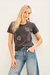 Remera básica de jersey color gris oscuro, con escote redondo y manga corta. Presenta bordados de corazones y estrellas doradas en el frente.