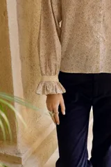 Camisa de algodón con estampado floral, cuello clásico, cierre frontal con botones, mangas largas con puños fruncidos y detalle de puntilla en puños y espalda.