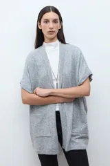 Ruana de tejido de punto color rosa melange, sin mangas y con cuello redondo.