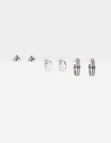 Set de aros plateados con pasante, que incluye aros tipo botón con diseño de nudo y aros tipo argolla de diferentes tamaños.