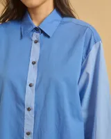Camisa celeste holgada de manga larga con bolsillo en el pecho y cuello clásico.