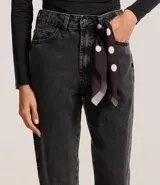 Pantalón mom de jeans con lavado oscuro, con trabillas en la cintura y pañuelo estampado de lunares atado como cinturón.