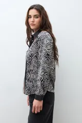 Camisa de manga larga con cuello camisero, estampado de cebra y detalles verticales en tonos negro, marrón y beige en el frente.