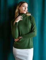 Polera de punto fino marca Nienty, color blanco, con cuello alto volcado y mangas largas con detalle de tajo en los puños.