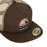 Gorro estilo trucker de color gris oscuro, con paneles traseros de malla negra. Presenta un parche frontal rectangular con un diseño de olas en tonos turquesa, blanco y gris, y el logo "HURLEY" en la parte inferior. Tiene visera plana y cordón decorativo en la unión de la visera y el cuerpo.