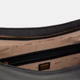 Bolso de hombro tipo hobo de Guess, color negro con textura granulada. Presenta herrajes y un dije frontal con el logo 'G' de Guess en tono dorado. Tiene una correa de hombro fina y detalles de argollas doradas a los costados.