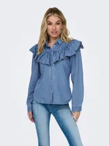 Camisa de denim celeste con cuello clásico, cierre frontal con botones dorados y mangas largas. Presenta volados en el frente y los hombros.