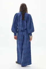 Camisa de lino a cuadros azules y celestes, con cuello camisero, mangas largas abullonadas y cierre frontal con botones.