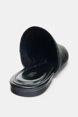 Zapato plano destalonado de piel color negro, con punta redonda y suela de 1,5 cm.