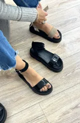 Sandalias negras con plataforma track y tira ancha sobre los dedos. Presentan una tira con hebilla alrededor del tobillo.