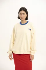 Buzo color crema de corte holgado, con cuello redondo y puños acanalados en color azul. Estampado pequeño con la frase "Karma Club" en el pecho.