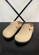 Zuecos color beige con plantilla de corcho y hebilla metálica ajustable.
