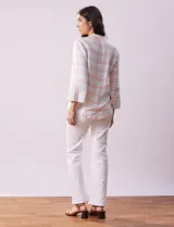 Blusa estampada a rayas horizontales en tonos celeste, blanco y naranja, con cuello mao, escote en V y abertura con botones. Delantero con punto smock. Manga ¾ con terminación amplia.