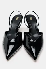 Zapato destalonado de charol negro con escote en pico, tira trasera ajustable y tacón fino.