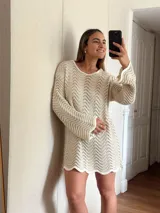 Vestido corto tejido en algodón y lurex color crudo, con punto pavo real, manga larga y escote en la espalda.