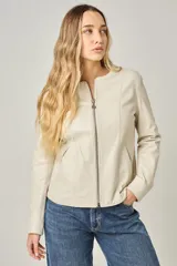 Campera de cuero color natural, con cuello redondo, cierre frontal con cremallera y bolsillos laterales con cierre. Diseño clásico y corte entallado.