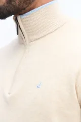 Sweater de tejido liso color verde oscuro, con cuello medio y cierre frontal parcial plateado. Presenta puños y cintura acanalados, y un pequeño logo bordado en el pecho.