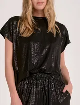 Enterito de silueta relajada confeccionado en tejido suave con lurex, color negro. Diseño de mangas cortas con escote a la base y laterales abiertos. Cintura elastizada y pantalón estilo jogger con terminación ajustada en el ruedo y bolsillos laterales.