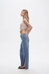 Pantalón de jean azul de tiro alto, corte recto y aberturas laterales en el ruedo.