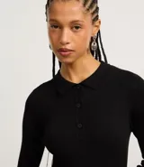 Vestido corto negro de punto con cuello polo, manga larga y botones en el escote.