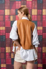 Chaleco color marrón de cuero sintético, con cuello en V, sin mangas, cierre frontal con un botón y dos bolsillos de parche.