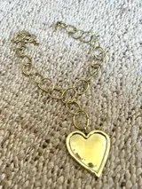 Collar dorado con cadena de eslabones grandes y dije de corazón martillado.