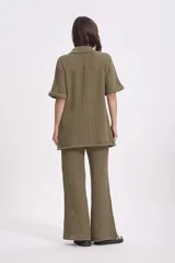 Sweater tejido color verde oliva, con cuello polo, manga corta y cierre frontal con botones. Tejido de punto acanalado.