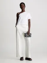 Riñonera negra Calvin Klein con diseño acolchado geométrico en forma de diamante, asa de mano de cadena plateada y correa de cintura ajustable y desmontable.