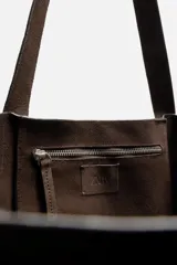 Bolso tipo shopper color marrón claro, fabricado en piel serraje. Cuenta con dos asas de mano y un bolsillo interior con cierre de cremallera.