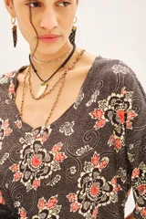 Vestido midi con estampado floral en tonos marrones, naranjas y blancos. Tiene mangas 3/4, escote en V y corte en línea A.