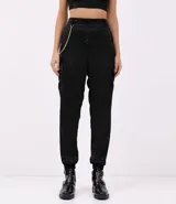 Pantalón jogger negro de poliéster con rayas laterales y cadena decorativa.