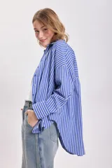 Camisa celeste con rayas verticales blancas, de corte holgado y mangas largas.