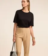 Pantalón de vestir azul marino, de corte zanahoria, con cinturón fino negro con hebilla dorada.