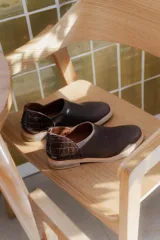 Zapato bajo color marrón con detalle de cuero texturizado en el talón.