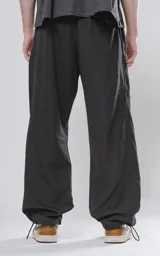 Pantalón negro de corte holgado con bolsillos laterales y cintura elástica ajustable con botón y cierre.