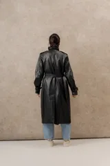 Trench largo de ecocuero negro, con diseño elegante y cierre lateral con botones.