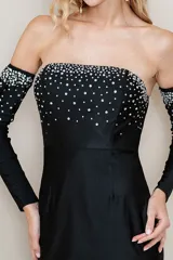 Vestido largo de fiesta negro, strapless, con mangas largas separadas y apliques de strass en el busto y en los puños.
