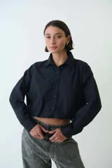 Camisa corta negra de corte holgado, abotonada al frente y con cuello camisero.