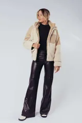Campera de borreguillo combinada en tonalidades beiges, con diseño moderno y bolsillos frontales.