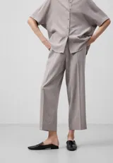 Pantalón tobillero color gris claro, de corte recto y cintura elástica. Presenta bolsillos de vivo con botón en la parte trasera.