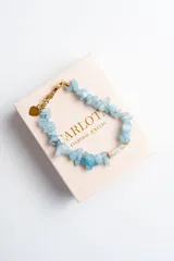 Pulsera de piedras naturales celestes y perla de agua dulce, con cierre de acero quirúrgico con baño de oro y dije de corazón dorado. Largo de 17cm y 4 cm de extensión.