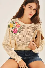 Sweater color crema de algodón con tejido calado y bordado de flores en el hombro.