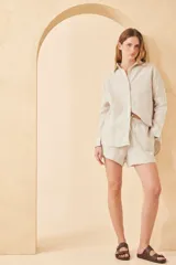 Camisa beige de lino, de corte holgado, manga larga y cuello clásico.