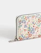 Billetera pequeña de cuerina estampada con diseño floral multicolor, cierre de cremallera y bolsillo frontal abierto.