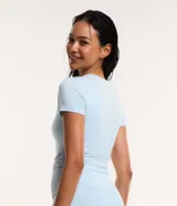 Remera cropped deportiva de poliéster y elastano, color blanco, con cuello redondo y mangas cortas.