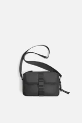Bandolera negra de acabado engomado, con compartimento principal con cierre de cremallera y bolsillo interior con cremallera. Bolsillo frontal con cierre de hebilla de liberación rápida. Asa de hombro ajustable y extraíble.